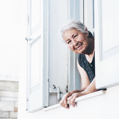elderly woman peering out a window